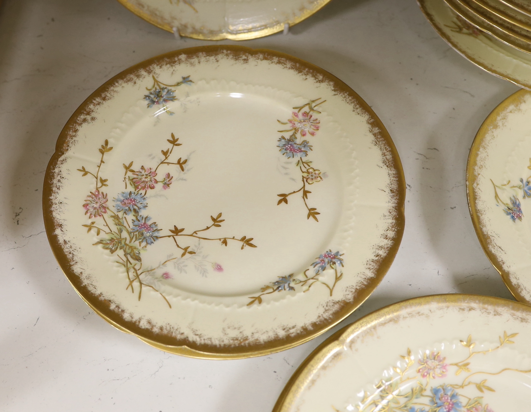 Thirteen Limoges style porcelain dessert plates, two on pedestal bases, gilt decorated with cornflowers etc., 24.5cm diameter